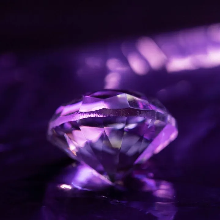 Faceted natural gemstone under violet light — MyGemsNFT tokenized gems